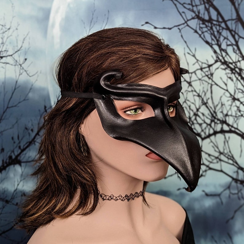 May include: A black leather masquerade mask with a long, pointed beak. The mask has a delicate design and is perfect for a masquerade ball or fancy dress party.
