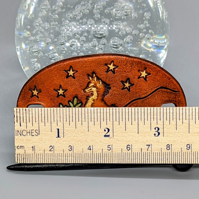 K&ouml;nnte beinhalten: Ein braunes Leder-Lesezeichen mit einem Fuchs- und Sternen-Design. Das Lesezeichen ist 5 cm lang.