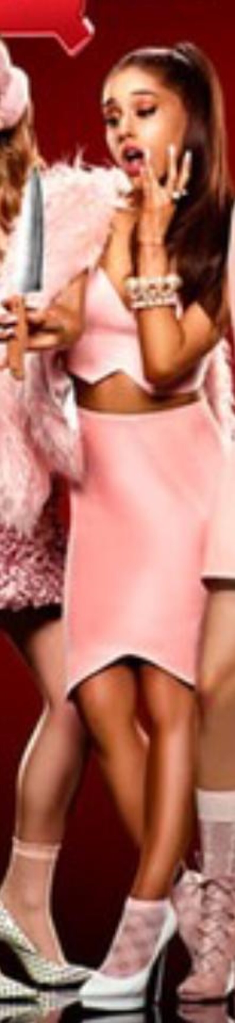 May include: A woman in a pink outfit, including a crop top and skirt, is surprised. She is wearing a pink fur jacket and high heels. Another person is holding a knife. The background is red.
