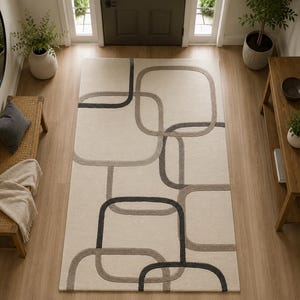 May include: A rectangular area rug featuring a cream-coloured background with an overlapping geometric pattern of rounded squares in shades of charcoal grey and light taupe, creating a textured, layered visual effect across the entire surface.