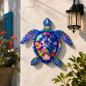 May include: A wall-mounted sea turtle decoration featuring a vibrant blue shell adorned with colorful floral and botanical patterns. The turtle has a patterned head and flippers with a blue and white mosaic-style design, creating a bright visual.