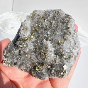 May include: A mineral specimen featuring a cluster of clear, translucent quartz crystals interspersed with metallic, gold-colored pyrite inclusions. The crystalline structure displays a jagged, irregular surface with varying textures.