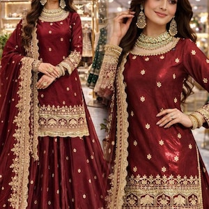Peut inclure: Une robe de cérémonie bordeaux brodée de détails dorés. La robe comprend un haut à manches longues et une jupe assortie, avec des broderies dorées complexes sur l'encolure, les manches et l'ourlet. L'ensemble comprend une écharpe assortie.