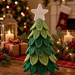 May include: A decorative crochet Christmas tree featuring layered green leaf-shaped segments in varying shades of light and dark green. The tree is topped with a white crocheted star and stands on a solid, light brown crocheted cylindrical base.