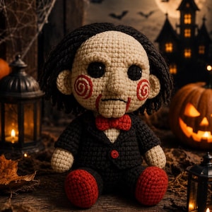 Peut inclure: Une poupée crochetée avec un visage pâle, des yeux noirs, des joues en spirale rouges et une ligne de bouche rouge. La poupée porte une veste de costume noire avec un bouton rouge, un nœud papillon rouge et des chaussures rouges.