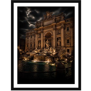 May include: A framed wall art print depicting the Trevi Fountain in Rome at night. The scene features the illuminated baroque architecture, central statue of Oceanus, and cascading water in the pool, set against a dark, dramatic cloudy sky.