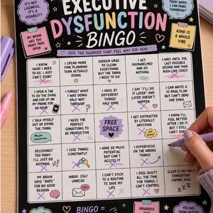 May include: A black rectangular Executive Dysfunction Bingo game board with white grid lines and colorful text. The board features various ADHD-related phrases in each square, with some squares marked with purple 'X' marks. Decorative elements include stars, hearts, and small icons.