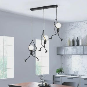 K&ouml;nnte beinhalten: Eine schwarze Pendelleuchte mit drei Lichtern und einem skurrilen Design. Jede Leuchte zeigt eine stilisierte Figur, die eine kugelf&ouml;rmige Gl&uuml;hbirne h&auml;lt. Die Leuchte ist an einer rechteckigen Basis aufgeh&auml;ngt und verleiht der Raumdekoration eine moderne Note.