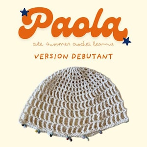 Peut inclure: Un bonnet en crochet de couleur crème avec une bordure perlée décorative. Le texte "Paola" en écriture orange est au-dessus du chapeau, avec "cute summer crochet beanie" en dessous. Les mots "VERSION DEBUTANT" sont également visibles.
