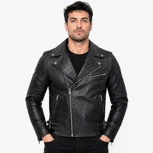 Peut inclure: Une veste de moto noire avec un motif texturé en peau de serpent, un col à revers cranté, des fermetures éclair métalliques argentées sur le devant et la poche poitrine, et des boucles latérales réglables à l'ourlet, portée sur un t-shirt noir.