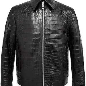 Puede incluir: Una chaqueta negra con una textura brillante en relieve de piel de cocodrilo en toda la prenda. La chaqueta incluye un cuello puntiagudo, mangas largas con puños y una cremallera metálica de color plateado en toda la parte frontal.