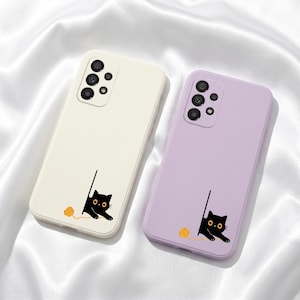 以下が含まれることがあります： クリーム色とラベンダー色の2つの携帯電話ケース。それぞれ黒猫のデザインが施されています。猫は黄色の毛糸玉で遊んでいます。ケースにはカメラモジュールが付いています。携帯電話用です。