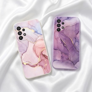 May include: Two phone cases with a marble design. One case is a light pink with gold accents, and the other is a deep purple with gold accents. Both cases have a glossy finish and a camera cutout.