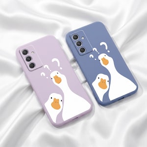 Può includere: Due custodie per telefono, una lilla e una blu, ciascuna con un design di oca dei cartoni animati. Le oche hanno corpi bianchi, becchi arancioni e sono accompagnate da punti interrogativi. Le custodie hanno ritagli per la fotocamera e posizionamenti dei pulsanti.