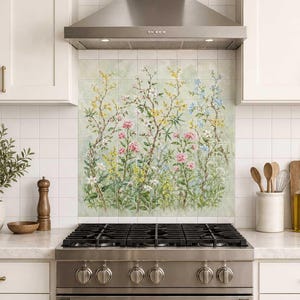 May include: A kitchen backsplash mural featuring a botanical illustration of various wildflowers, including pink peonies, yellow blossoms, and blue flowers on thin brown stems, set against a soft green watercolor background behind a stainless steel stove.