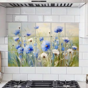 Könnte beinhalten: Ein Satz Blumentafeln mit einem Aquarellgemälde aus blauen und weißen Wildblumen auf einem Feld. Das Kunstwerk wird als Spritzschutz über einem Küchenherd ausgestellt und verleiht der Einrichtung einen Hauch von Natur.