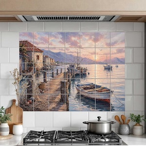 May include: A decorative tile mural featuring a coastal scene with a wooden pier extending into calm water. A small boat is moored alongside the pier, with a stone building on the shore and mountains in the distance under a soft pink sunset sky.