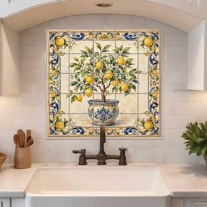 May include: A kitchen backsplash featuring a tile mural of a lemon tree in a blue and white pot. The mural is surrounded by a decorative border with yellow lemons and blue accents. The kitchen has white cabinets and a white sink.