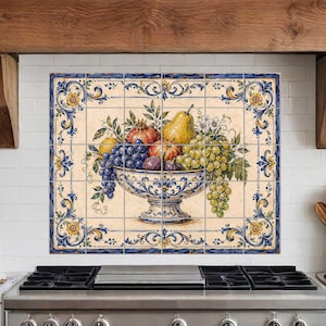 May include: A decorative tile backsplash featuring a still life of fruit in a blue and white bowl. The fruit includes grapes, pears, and pomegranates. The tile has a blue and yellow floral border and is installed above a stainless steel stove.