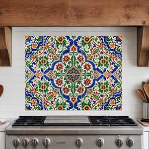 May include: A colourful tile backsplash with a repeating floral pattern in blue, red, green, and yellow. The tiles are installed above a stainless steel gas hob in a kitchen. The overall design is symmetrical and decorative.