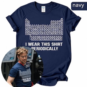 Op de afbeelding: Een marineblauw t-shirt met korte mouwen en een witte afbeelding van het periodiek systeem der elementen op de borst. Onder de tabel staat de tekst I WEAR THIS SHIRT PERIODICALLY in witte hoofdletters. Het shirt heeft een ronde hals.