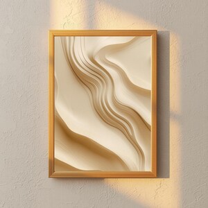 May include: A rectangular wall art piece featuring an abstract design of flowing, layered cream and beige waves encased in a simple gold-toned frame. The artwork displays smooth, curved lines that create a sense of depth and movement.