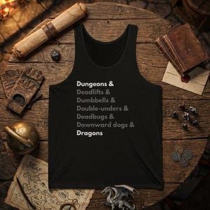 May include: A black tank top featuring white and grey text that reads: Dungeons & Deadlifts & Dumbbells & Double-unders & Deadbugs & Downward dogs & Dragons. The design is centered on the front of the garment, which has a classic sleeveless cut.