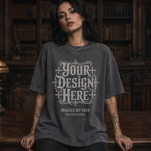 May include: Dark gray t-shirt with the text "YOUR DESIGN HERE" in a decorative font. The shirt is a mockup from Mocks by Issy Mockup Studio. The shirt has short sleeves and a relaxed fit.