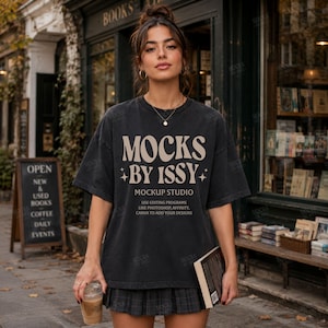 以下が含まれることがあります： ベージュの文字「MOCKS BY ISSY MOCKUP STUDIO USE EDITING PROGRAMS LIKE PHOTOSHOP, AFFINITY, CANVA TO ADD YOUR DESIGNS」と小さな星のアイコンがプリントされたチャコールグレーのオーバーサイズTシャツと、ダークグレーのプリーツミニスカート。