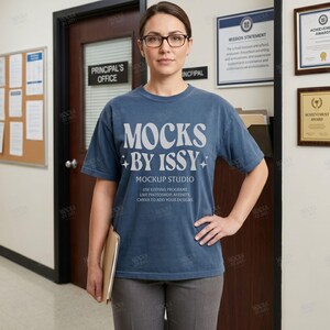 Op de afbeelding: Een blauw t-shirt met korte mouwen voorzien van de witte tekst MOCKS BY ISSY MOCKUP STUDIO en instructies voor het gebruik van bewerkingsprogramma's zoals Photoshop, Affinity en Canva om ontwerpen toe te voegen. Het shirt heeft een ronde hals.