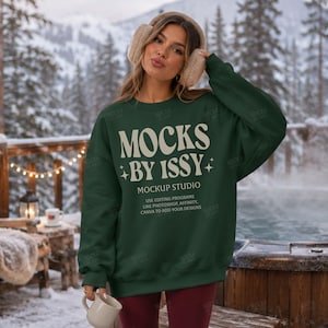 Könnte beinhalten: Ein dunkelgrünes Langarm-Sweatshirt mit dem weißen Text MOCKS BY ISSY MOCKUP STUDIO USE EDITING PROGRAMS LIKE PHOTOSHOP, AFFINITY, CANVA TO ADD YOUR DESIGNS und kleinen Sternsymbolen, getragen mit beigen, flauschigen Ohrenschützern.