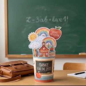 May include: A cylindrical container featuring a school-themed design with a red schoolhouse, rainbows, clouds, a sun, and a red apple. The front displays a chalkboard graphic with the text "DANKE FÜR DIE ZEIT!" and an apple illustration.