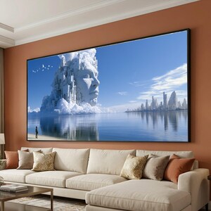 May include: A large rectangular wall art print featuring a surreal landscape with a giant white stone face emerging from clouds above a calm blue sea. A distant city skyline sits on the horizon, and a small silhouette of a person stands on the shore.