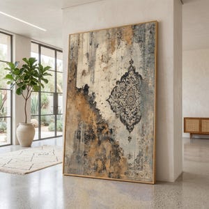 Könnte beinhalten: Großer gerahmter abstrakter Kunstdruck mit einem Used-Design. Das Kunstwerk zeigt ein zentrales, verziertes Muster in Schwarz und Grau vor einem Hintergrund aus Beige-, Gold- und Grautönen. Der Rahmen hat eine helle Holzfarbe.