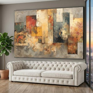 May include: Large abstract painting with a black frame. The artwork features a collage of rectangular shapes in shades of red, yellow, gray, and blue. A tufted, cream-colored sofa sits below the painting, with a potted plant to the left.