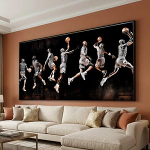 May include: A large framed artwork depicting a sequence of a basketball player in mid-air, dunking the ball. The artwork is in black and white with a dark background. The player is wearing a jersey and shorts. The artwork is displayed above a cream-colored sofa.