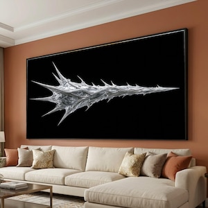 Puede incluir: Una gran pieza de arte mural rectangular que presenta una forma orgánica plateada, metálica y puntiaguda, centrada sobre un fondo negro sólido. La obra está enmarcada con un borde negro fino y se muestra horizontalmente en una pared de color terracota.