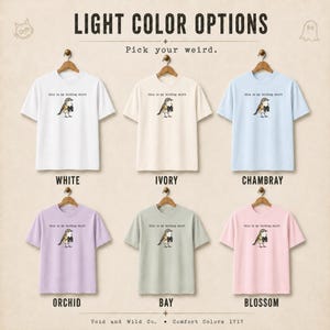 May include: Six short-sleeve t-shirts in white, ivory, chambray, orchid, bay, and blossom colors. Each shirt features a graphic of a bird holding binoculars with the text "this is my birding shirt" above it. The image includes the text "LIGHT COLOR OPTIONS" and "Pick your weird."