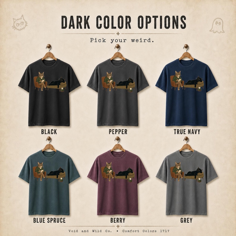 May include: Six short-sleeve t-shirts in black, pepper, true navy, blue spruce, berry, and grey. Each shirt features a graphic of a cat sitting in a chair reading and a black cat lying on a couch. Text reads: DARK COLOR OPTIONS, Pick your weird.