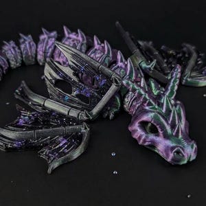 May include: A detailed, articulated dragon figurine in shades of purple, black, and green. The dragon is posed on a dark surface, with its head, wings, and segmented body clearly visible. The design features intricate details and a fantasy theme.