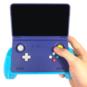 Può includere: Una console di gioco portatile blu e verde acqua, con un grande schermo nero e vari pulsanti, tra cui un pad direzionale, pulsanti azione e un joystick. La console è tenuta in una mano.