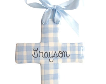 May include: A blue and white gingham cross with the name Grayson written in black cursive. The cross has a blue ribbon tied around the top.