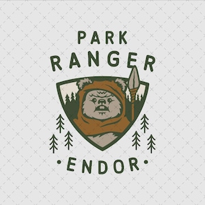 Peut inclure: Une illustration graphique représentant une créature brune et poilue portant une capuche à l'intérieur d'un emblème en forme de bouclier. Le texte PARK RANGER est arqué au-dessus et ENDOR en dessous. Le design inclut des pins vert foncé.
