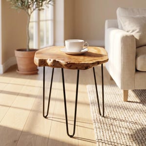 May include: A small, natural wood side table with a live edge and black hairpin legs. A white teacup and saucer sit on the table's surface. The table is approximately 24 inches in diameter and 18 inches tall.