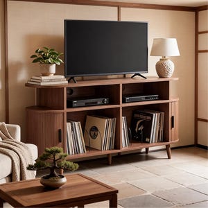 May include: A walnut-toned media console featuring rounded side cabinets with vertical slats, open shelving for electronics, and storage for vinyl records. A flat-screen television sits on top alongside a potted plant and a textured table lamp.
