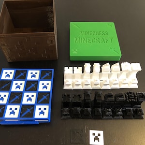 Peut inclure: Un jeu d'échecs sur le thème de Minecraft. Il comprend une boîte marron, un couvercle vert avec le texte "Minechess Minecraft", un échiquier bleu et blanc et des pièces d'échecs noires et blanches.