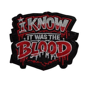 Peut inclure: Écusson brodé noir avec le texte "I KNOW IT WAS THE BLOOD" en rouge et blanc. L'écusson a une forme unique avec une étoile en haut et un motif de sang qui coule.