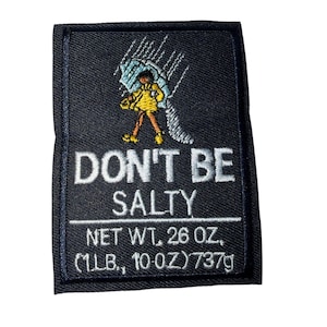 Pode incluir: Patch bordado com o texto "DON'T BE SALTY" em branco sobre fundo preto. O patch apresenta uma ilustração de uma pessoa com capa de chuva amarela e guarda-chuva azul. O patch tem 737g, equivalente a 26 oz (1 lb, 10 oz).