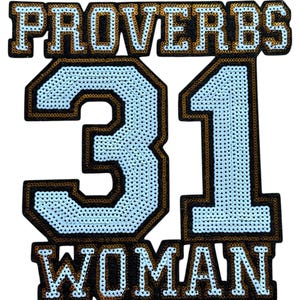 May include: A sequined patch with the words "PROVERBS 31 WOMAN" in white letters outlined in black and gold. The number "31" is in a light blue color, also outlined in black and gold. The patch is on a white background.