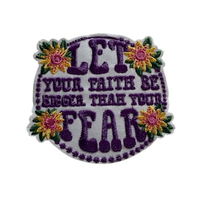 May include: Embroidered patch with the text "LET YOUR FAITH BE BIGGER THAN YOUR FEAR" in purple on a white background. The patch is decorated with floral accents in yellow, pink, and green.